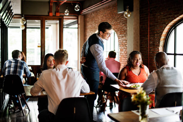 Waiter serving guests in busy restaurant with brick walls